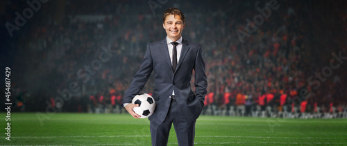 smiling businessman in formal wear with soccer ball in the big stage photo