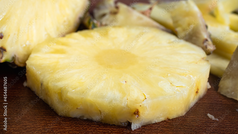 Over ripe pineapple, sliced up on a wooden cutting board. The juicy yellow interior shines brightly in this highly detailed close up of the flesh of the pineapple. Fruit and food conservation concept.