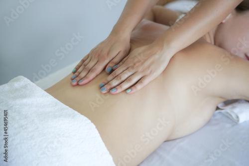 Fototapeta Naklejka Na Ścianę i Meble -  Back, neck and shoulder massage in the spa salon. Young woman receiving a luxurious oil massage treatment, relaxing rejuvenation pampering therapy at the resort spa.