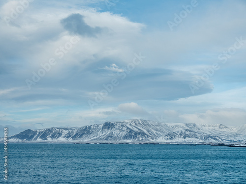 Rocky snowy coast washed by rippling blue sea © Dund Photography