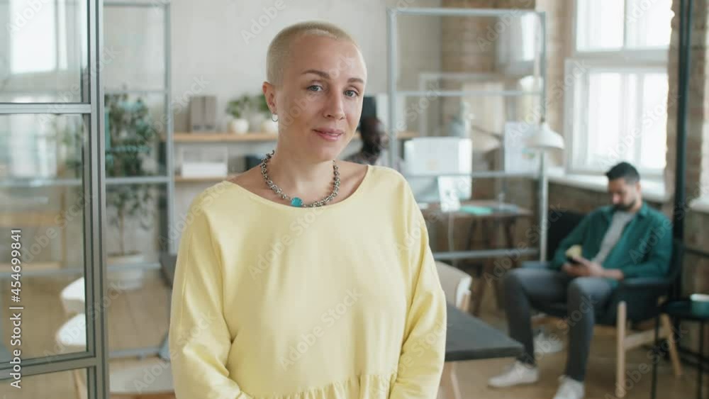 Waist up portrait of cheerful Caucasian businesswoman with short hair standing in office and looking at camera with smile Waist up portrait of cheerful Caucasian businesswoman with short hair standing in office and looking at camera with smile