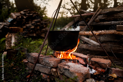 Bonfire with a pot for cooking at night in the camp. Hiking and camping in the woods, cooking dinner on the fire.