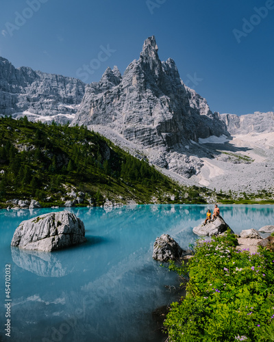 Morning with clear sky on Lago di Sorapis in the Italian Dolomites, milky blue lake Lago di Sorapis, Lake Sorapis, Dolomites, Italy. Couple man and woman mid age walking by the lake in the mountains  photo