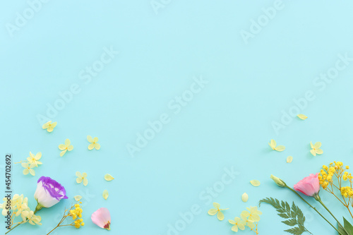 Top view image of pink  yellow and purple flowers composition over pastel blue background .Flat lay