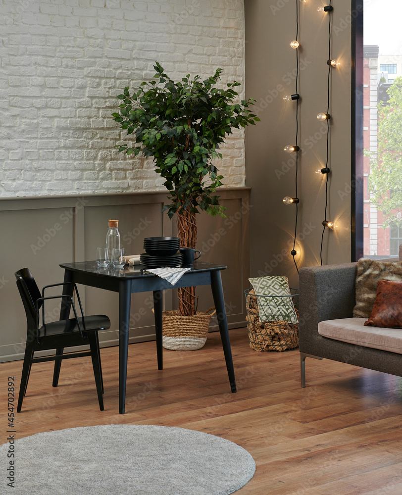 Fototapeta premium Carpet detail in the room, kitchen table, black chair and grey sofa, lamp, plant and bookshelf background.