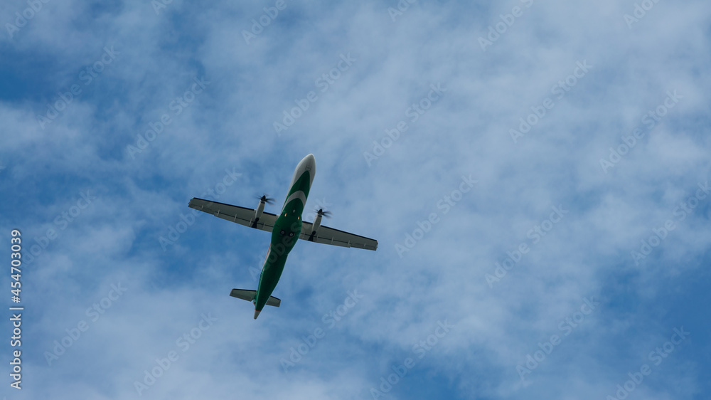 View of propeller plane flying low with blue sky and clouds at background. View of propeller plane flying low with blue sky and clouds at background.