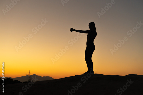 Silueta de chica haciendo técnica de boxeo, en la montaña a la hora del atardecer, con espacio para texto.