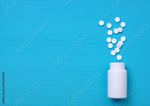 Pills, tablets and bottle on blue background.