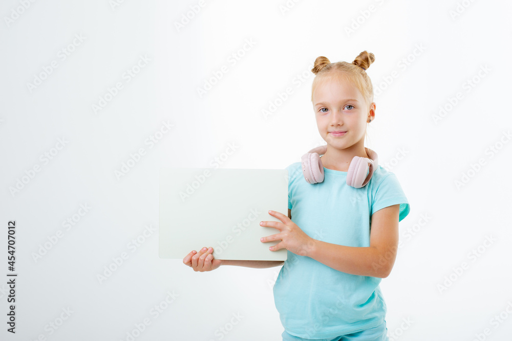 a little girl in headphones holds a white sheet of paper on a white background isolated a little girl in headphones holds a white sheet of paper on a white background isolated