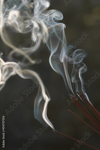 A beautiful pattern of flowing incense smoke. Illuminated smoke from a large number of aroma sticks. Background for design. Vertical format.