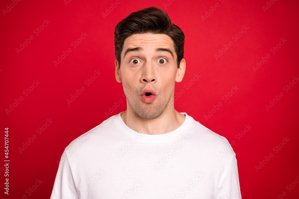 Photo of impressed brunet young guy wear white shirt isolated on red color background Photo of impressed brunet young guy wear white shirt isolated on red color background
