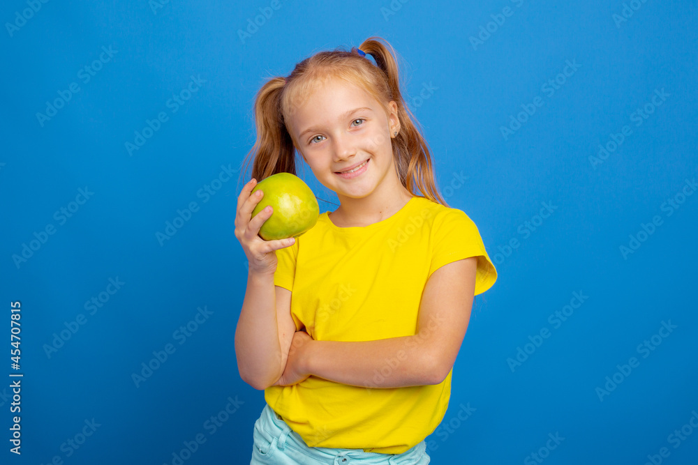 a little girl holds an apple on a blue background a little girl holds an apple on a blue background