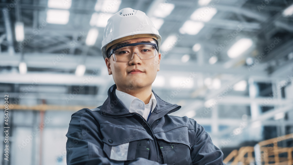 Portrait of a Professional Asian Heavy Industry Engineer Wearing Safety Uniform, Glasses and Hard Hat, Looking into the Camera. Confident Chinese Industrial Specialist Standing in a Factory Facility. Portrait of a Professional Asian Heavy Industry Engineer Wearing Safety Uniform, Glasses and Hard Hat, Looking into the Camera. Confident Chinese Industrial Specialist Standing in a Factory Facility.