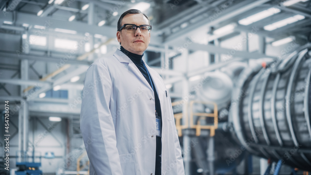 Portrait of a Professional Male Heavy Industry Engineer/Worker Wearing White Laboratory Coat and Safety Glasses. Confident Caucasian Industrial Specialist Standing in a Factory Facility. Portrait of a Professional Male Heavy Industry Engineer/Worker Wearing White Laboratory Coat and Safety Glasses. Confident Caucasian Industrial Specialist Standing in a Factory Facility.