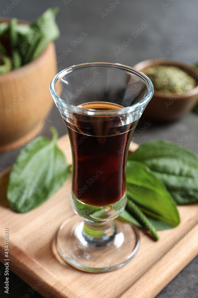 Glass of broadleaf plantain oil on wooden board Glass of broadleaf plantain oil on wooden board
