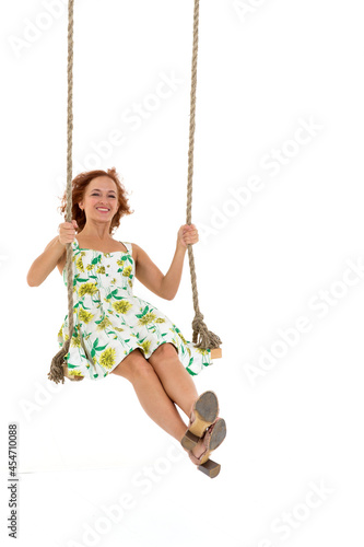 Beautiful young woman swinging on rope swing photo