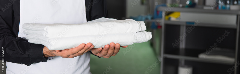 cropped view of housekeeper holding clean bed sheets, banner cropped view of housekeeper holding clean bed sheets, banner