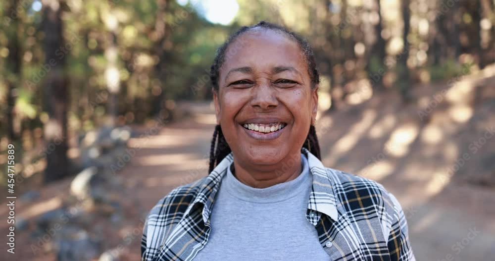 African senior woman smiling on camera with forest in background African senior woman smiling on camera with forest in background