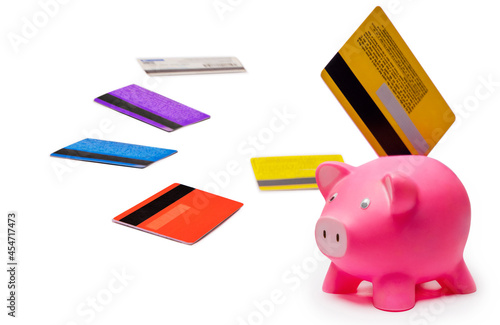 A credit card inserted in piggy bank with other credit cards alongside. photo