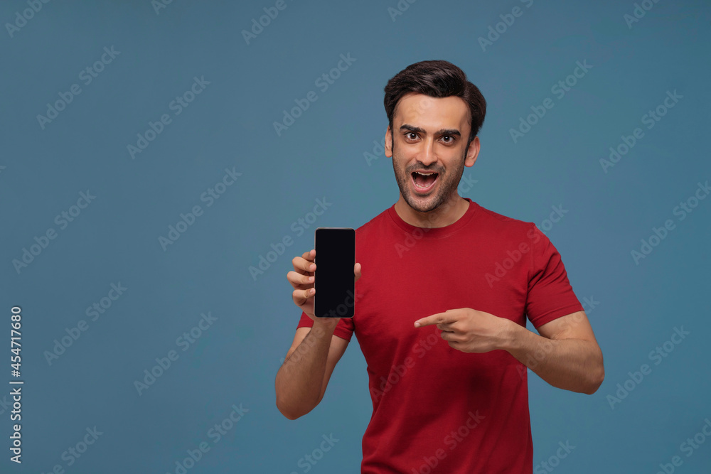 Portrait of a young man showing mobile phone in his hand against plain background. Portrait of a young man showing mobile phone in his hand against plain background.