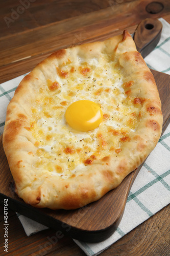 Fresh homemade khachapuri with cheese and egg on wooden table