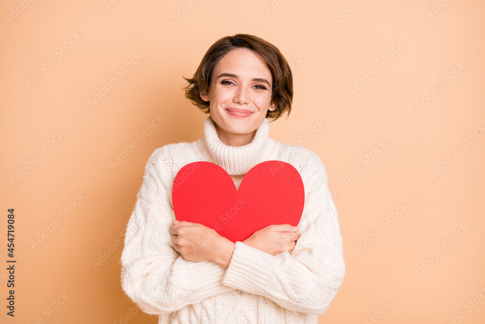 Photo of adorable cute young lady hold embrace big red paper heart love isolated on beige color background Photo of adorable cute young lady hold embrace big red paper heart love isolated on beige color background