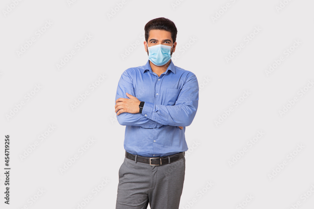 Portrait of a man with mask on face standing with hands crossed against plain background. Portrait of a man with mask on face standing with hands crossed against plain background.
