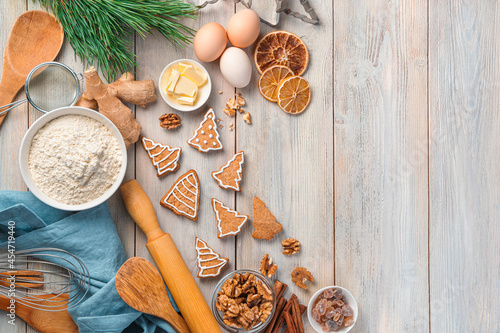 Ginger cookies, ingredients and a pine branch on a beige background.