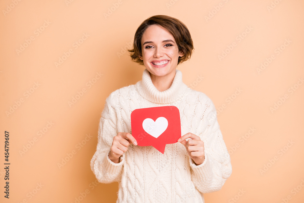 Photo portrait of female student showing heart icon social media browsing internet smiling isolated on pastel beige color background Photo portrait of female student showing heart icon social media browsing internet smiling isolated on pastel beige color background