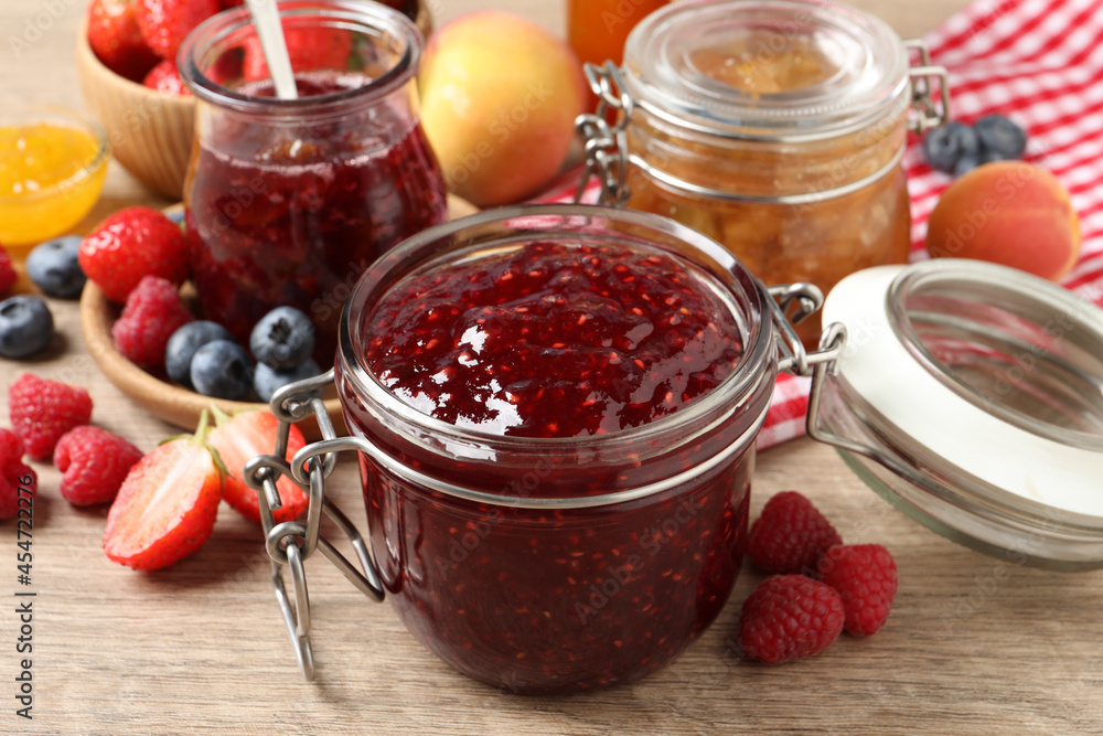 Jars with different jams and fresh fruits on wooden table, closeup Jars with different jams and fresh fruits on wooden table, closeup