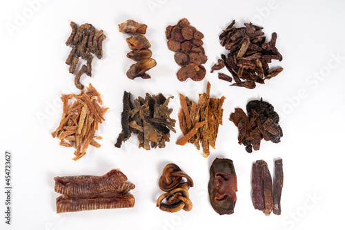 Various dehydrated beef and chicken products for dogs (trachea, noses, ears, necks, cut lungs, udder, liver, heart, stomach, testes and penis). Homemade pet treats. White background, copy space.