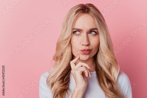 Portrait of doubtful clever jealous girl finger cheek look blank space on pink background