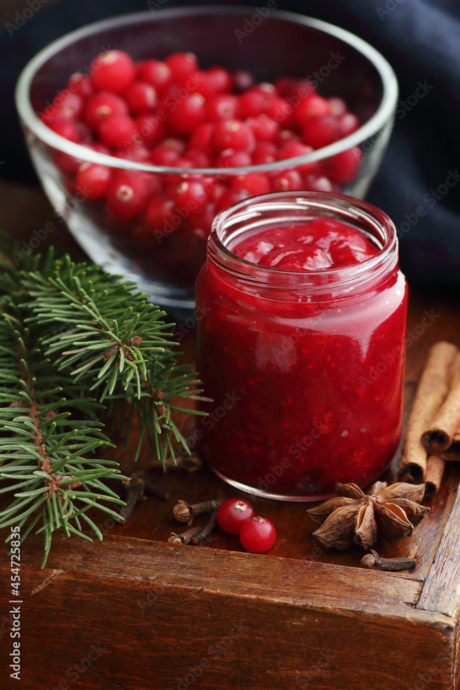 Cranberry sauce in a flas jar on rustic background, traditional holiday berry jam for christmas or thanksgiving, closeup, copy space, healthy homemade canned food concept