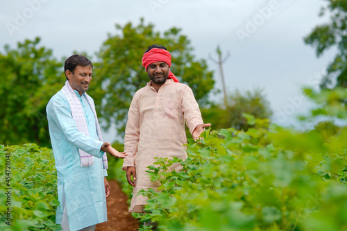 Two indian farmers talking at cotton agriculture field.