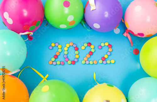 holidays, celebration and decoration concept - 2022 new year party date with colorful balloons on blue background