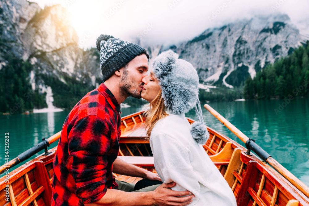 Romantic couple visiting an alpine lake at Braies Italy - Tourists in love spending loving moments together at autumn mountains - Love, wanderlust and travel concept.