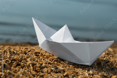 White paper boat near river on sunny day, closeup