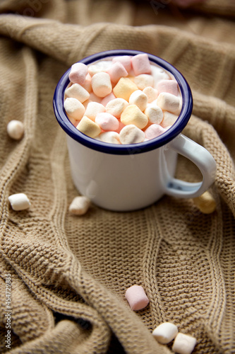 season, leisure and objects concept - camp mug full of marshmallow on knitted blanket