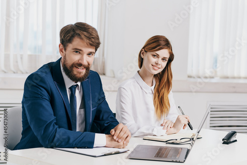 business man and woman talking at the table in front of laptop professionals technology