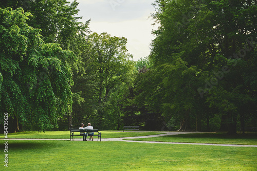 Two elderly people sit on a bench in a Park