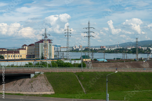 A highway with an overpass against the background of an industrial city by the river. © Vectorina