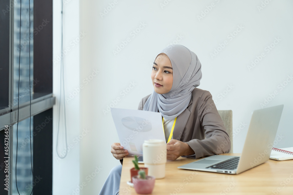 Asian Muslim business woman in hijab headscarf working with with paper ...