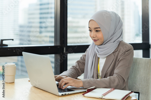 Canvas-taulu Asian Muslim business woman in hijab headscarf working with computer laptop in the modern office