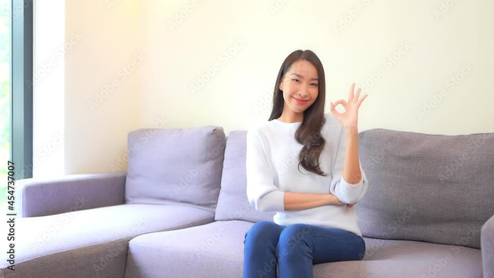Beautiful Asian Woman on Couch Making OK Hand Gesture SLOMO Beautiful Asian Woman on Couch Making OK Hand Gesture SLOMO