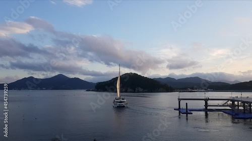 Catamaran Boat Cruising Off The Pier Of Hanwha Resort In Geojedo Island, South Korea. wide shot photo