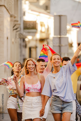 Multiracial men and women walking with rainbow flags during pride parade