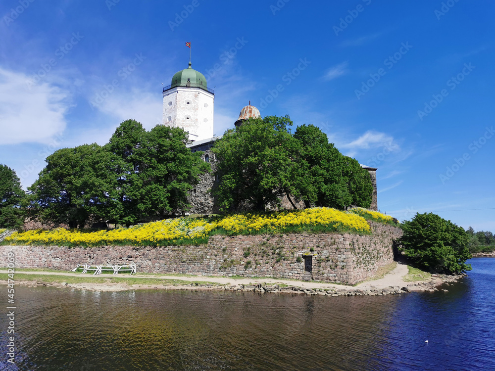 Against the background of a blue sky with feathery clouds, Vyborg Castle and the white Tower of St. Olaf in the city of Vyborg.