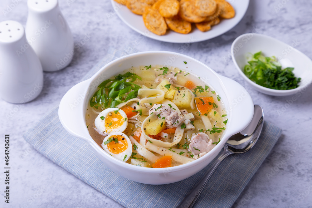 Soup with chicken, noodles, potatoes, quail eggs and carrots. Seasoned with onions and parsley. Close-up. Soup with chicken, noodles, potatoes, quail eggs and carrots. Seasoned with onions and parsley. Close-up.