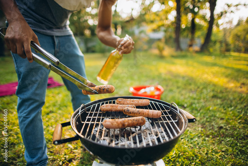 Barbecue. Croppe image of man flipping grilled sausage photo