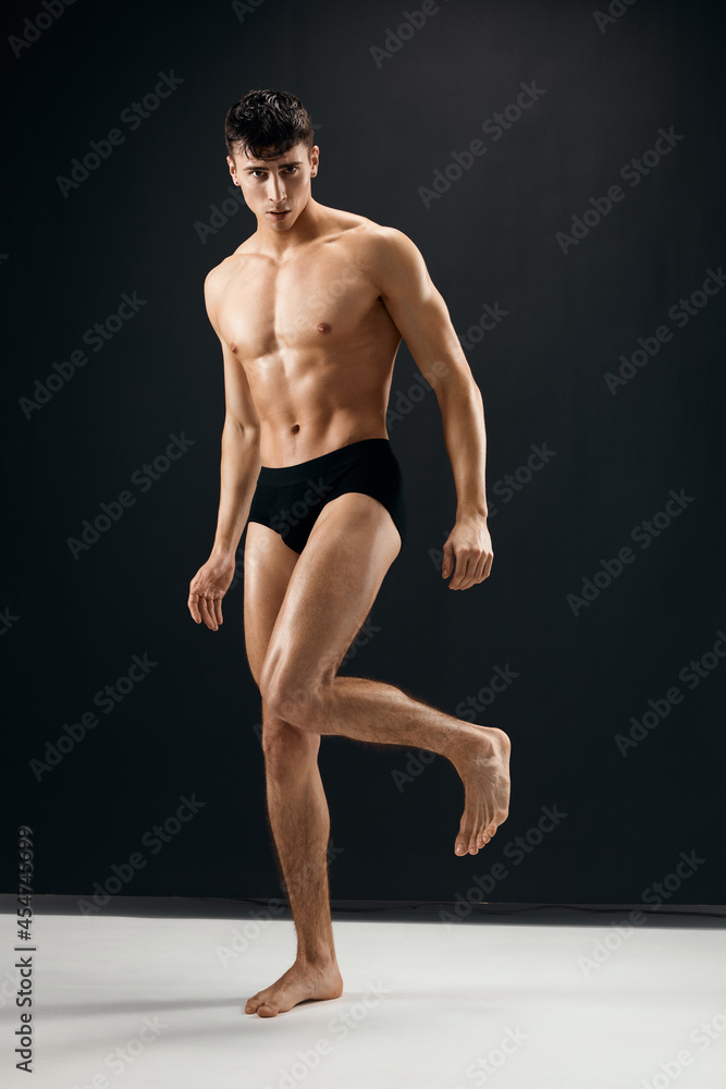 Obraz premium sporty man in black shorts with a pumped body on a dark background model